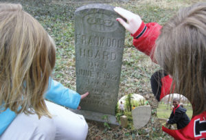 Close-up of students examining a headstone