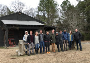 A group of students and faculty stand at the farm