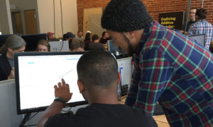Two students look at a computer monitor together.