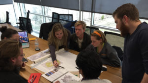 Students gathered around a table review sketches