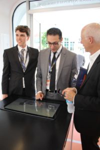 Two students and Dean Scott Poole operating a touch screen inside of AMIE.