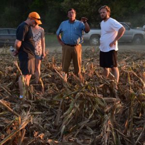 A group of students and a farmer stand in a dry corn field in the Tennessee River floodplain
