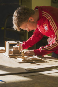 A male student works on a project in the wood shop