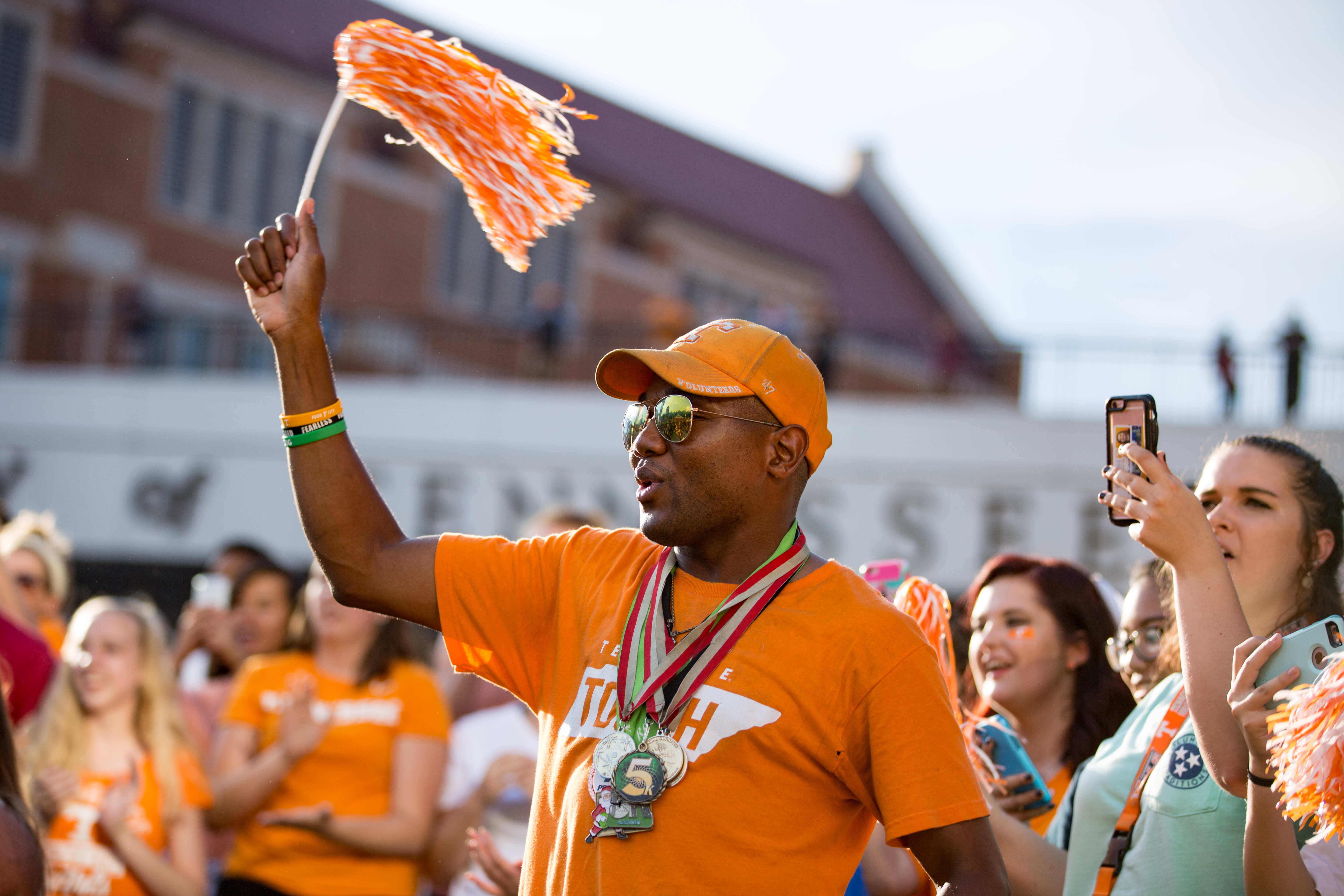 A male dressed in orange waves his pom during the pep rally before the first football game of the season.