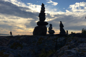 Silhouettes of balanced stacked rocks against the sunset.