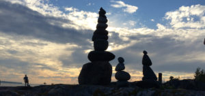 Silhouettes of balanced stacked rocks against the sunset.