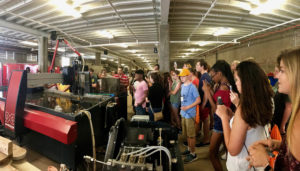 Students watch a demonstration of one of the large machines in the Fab Lab