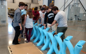 Students interact with curved 2.5-foot-tall blue tube