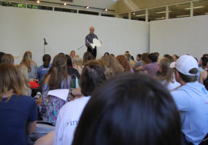 Dean Poole presenting to students holding a chair