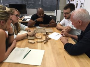 A group of people around a table discussing sketches and models.