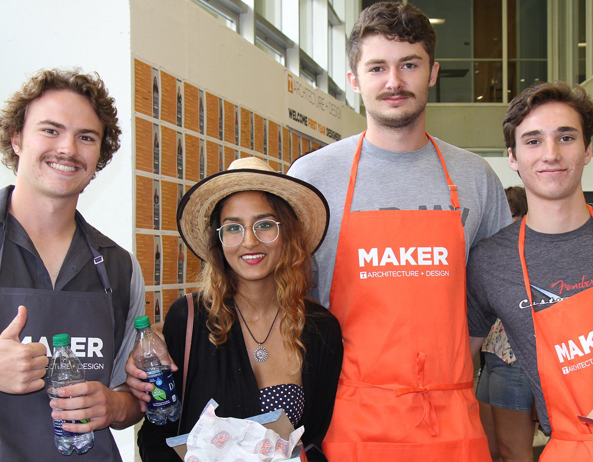 A group of students wearing orange "Maker" aprons.