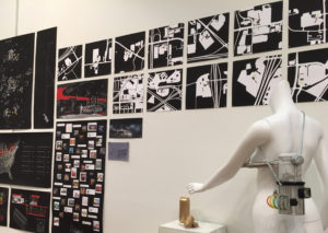 A wall filled with work, primarily black and white, with a human mannequin in the foreground.