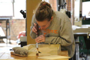 A female student works on a project in the wood shop