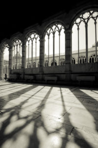 The shadows of intricate arched windows cast on the floor.
