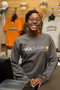 A young woman wearing a VolShop shirt stands in the bookstore.