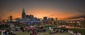 Nashville's skyline at sunset with a park filled with people in the foreground.