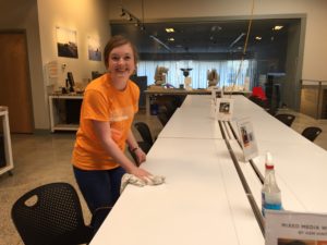 A young woman in an orange shirt cleans a space in preparation for a special event