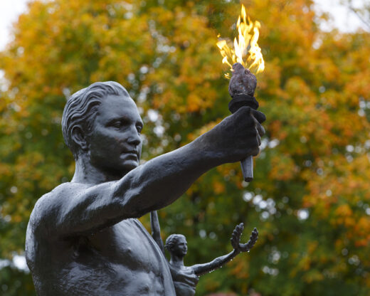 A bronze statue of a man and woman on the UT campus holding a flaming torch.