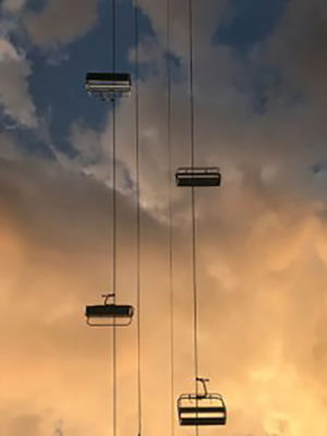 Chairs on wires with clouds behind
