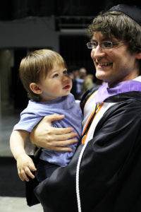 student holding baby at graduation