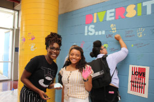 Students smiling after contributing to the wall