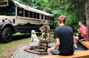 Caleb Brackney plays guitar outside Roamer bus