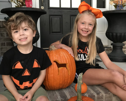 two children with Jack o'lanterns on porch