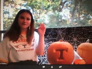 student demonstrates carving a pumpkin