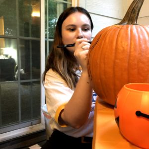 student stenciling on a pumpkin