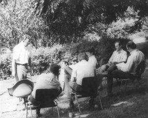 black and white photo of group of students and teacher in chairs outside