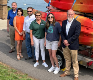 group of people standing with orange kayaks