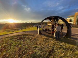 people assembling 3D printed pavilion with setting sun