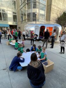 young students draw at tables near Airstream