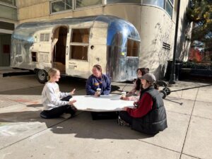 students sitting at low table outside of Airstream table