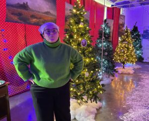 student standing in front of Christmas trees