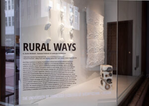 Exterior of the 500 S. Gay Street building with the Rural Ways exhibition. On a glass panel, 'Rural Ways' and the exhibition statement.