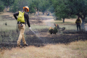 Jeremy Magner pours water from a sack on his back during a controlled burn exercise in California.
