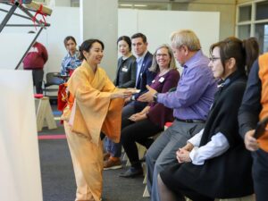 Asian woman hands tea to members of the campus and Knoxville community watch and participate in a traditional Japanese tea ceremony.