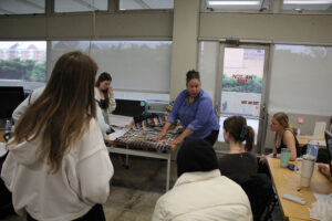 Felicia Francine Dean, Assistant Professor in the School of Interior Architecture, works with students on their weaving project inside the Art + Architecture Building.