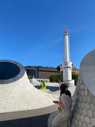 Caroline Robertson, in the foreground, at the Amos Rex art museum in Helsinki, Finland. The distinctive white, undulating structures in the foreground are the skylights and rooftop domes of the museum, which is known for its unique architecture.