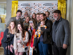 A family gathers around their graduate at a photo booth during the college's commencement celebration on Friday, December 13, 2024.