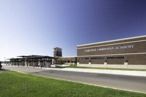 Exterior view of Lakeway Christian Academy showcasing its modern brick facade, prominent tower, and covered walkway under a clear blue sky.