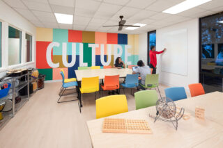 Interior a multipurpose room at Park Center Woodland Renovation. The back wall features a custom mural of blocked colors featuring the word, 