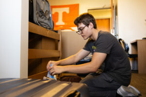 Student unpacking luggage inside of dorm in Brown Hall during move in week.