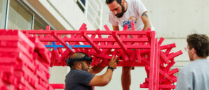 Two graduate students assist Marshall Prado in building a deer stand/duck blind using augmented reality.
