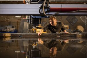 A student removes cut materials from an abrasive waterjet cutter inside the UT Fab Lab during a staged photoshoot for a College of Architecture and Design annual report on October 29, 2020. Photo by Steven Bridges/University of Tennessee