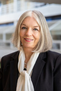 Headshot of Marleen Kay Davis in the Art and Architecture Building. She is wearing a blue blazer with a white neck scarf.