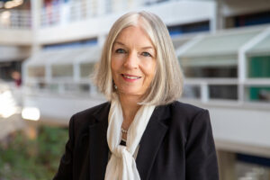 Headshot of Marleen Kay Davis in the Art and Architecture Building. She is wearing a blue blazer with a white neck scarf.