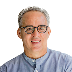 Headshot of a man with short gray hair and round glasses, wearing a light blue button-down shirt.